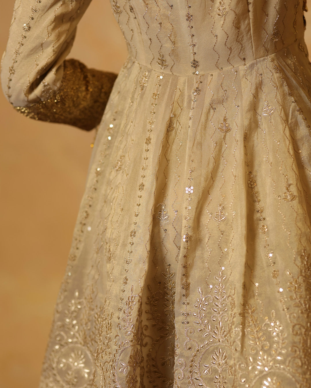Close-up of a beige embroidered dress with intricate patterns on a blurred background