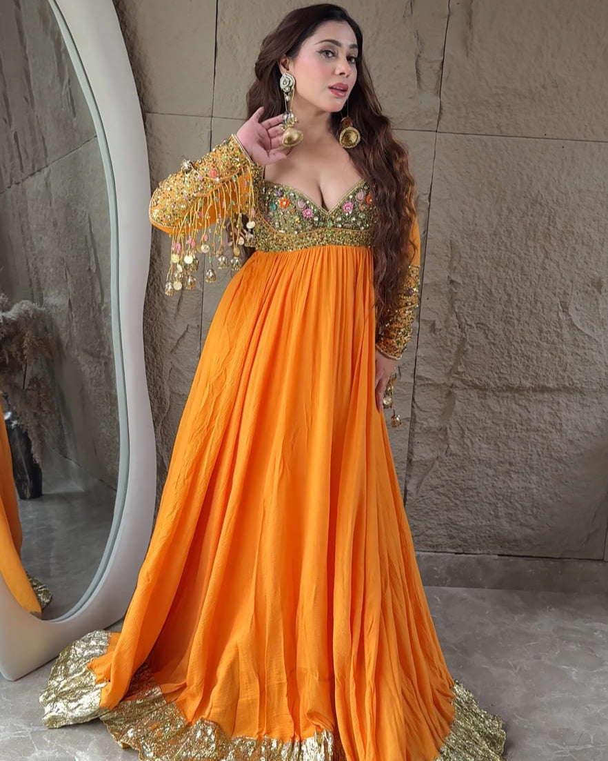 Woman in an orange and gold traditional outfit standing in front of a mirror.