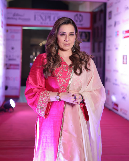Woman in a pink and white saree at an event with a blurred background